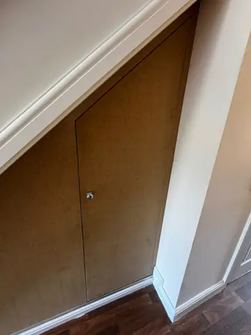 Fitted timber cupboard doors beneath a staircase