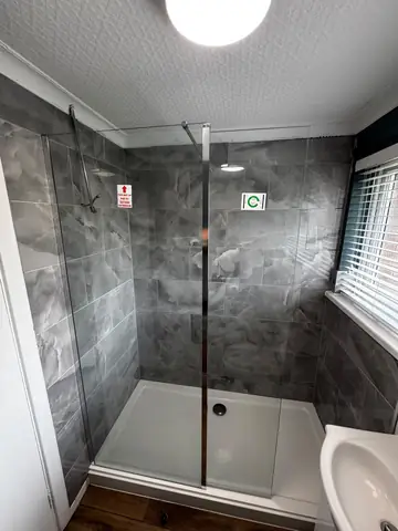 New shower screen and tray fitted against grey wall tiles