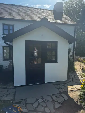 Front view of a white porch with dark fascia and entrance door