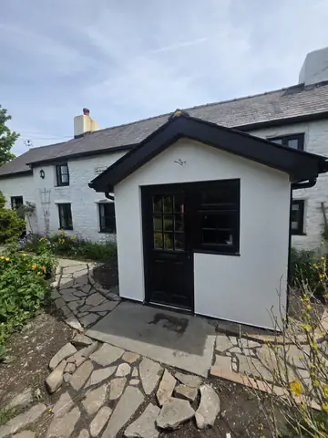 White porch with dark window frames, entrance door and pitched roof