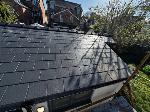 Fully covered slate roof with ridge tiles and guttering, with scaffolding below